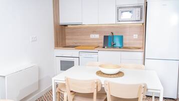 Uma cozinha moderna com armários brancos, micro-ondas, pia e uma mesa de jantar com cadeiras.