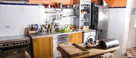 A kitchen with a stove, oven, and a wooden table with a cutting board.