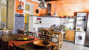 A kitchen with a wooden table, chairs, a washing machine, and a microwave.
