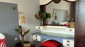 Hotelkamer met een bed, bureau, stoel, spiegel en nachtkastje met een bloevas.