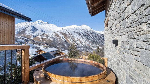 A wooden hot tub with a stone wall and a mountain view. - Spacious chalet with Nordic bath and steam room in Saint-Martin-de-Belleville (Saint-Martin-de-Belleville)