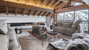 A cozy living room with a fireplace, wooden beams, and a view of snowy mountains. - Spacious chalet with Nordic bath and steam room in Saint-Martin-de-Belleville (Saint-Martin-de-Belleville)
