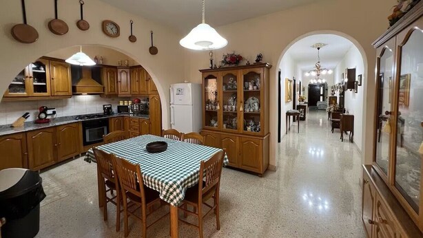 Uma cozinha ampla com armários de madeira, uma mesa de jantar com cadeiras e um candelabro.