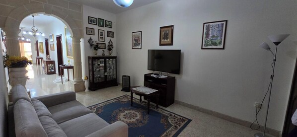 A living room with a sofa, a TV, a cabinet, and a rug. - Lourdes House (San Gwann)