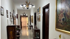Um corredor com lustre, obras de arte emolduradas e uma área de jantar com cadeiras e mesa.