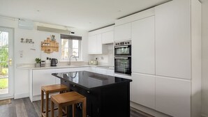 Een moderne keuken met witte kasten, een zwart kookeiland en houten krukken.