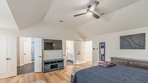 Una camera da letto con un grande letto, una ventola a soffitto, una TV a schermo piatto e un armadio a tutta parete.