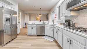 Una cucina moderna con elettrodomestici in acciaio inossidabile, mobili bianchi e un'isola centrale.