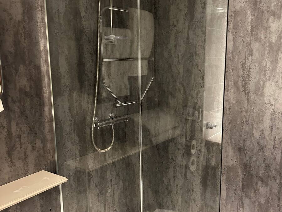 Een moderne douchecabine met een glazen deur en een handdouche.