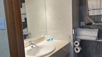 A modern bathroom with a sink, mirror, towel rack, and toilet.