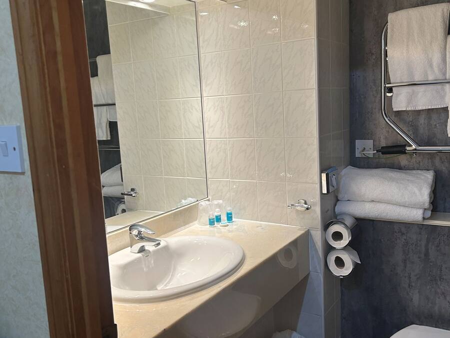 A modern bathroom with a sink, mirror, towel rack, and toilet.