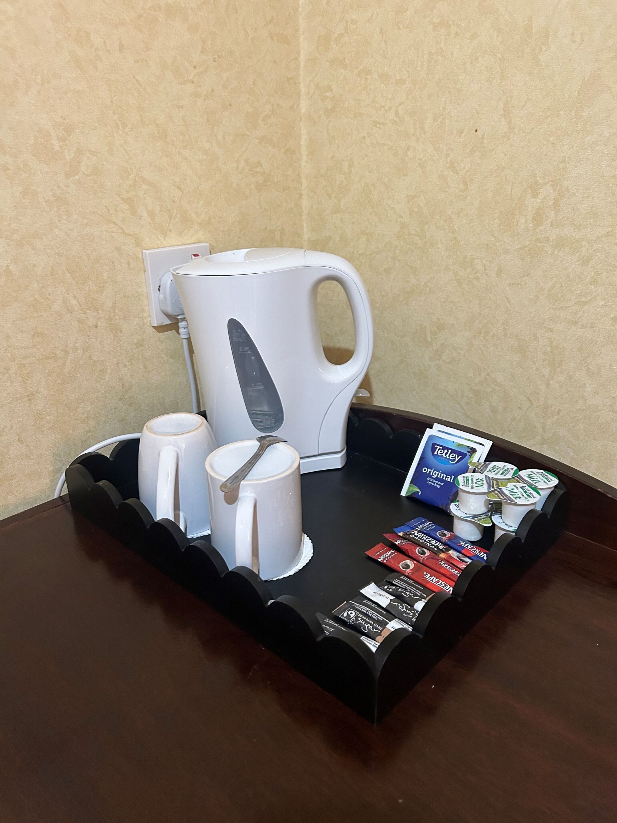 A tray with a coffee maker, two white mugs, and a selection of coffee pods.