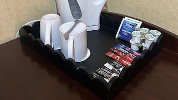 A tray with a coffee maker, two white mugs, and a selection of coffee pods.