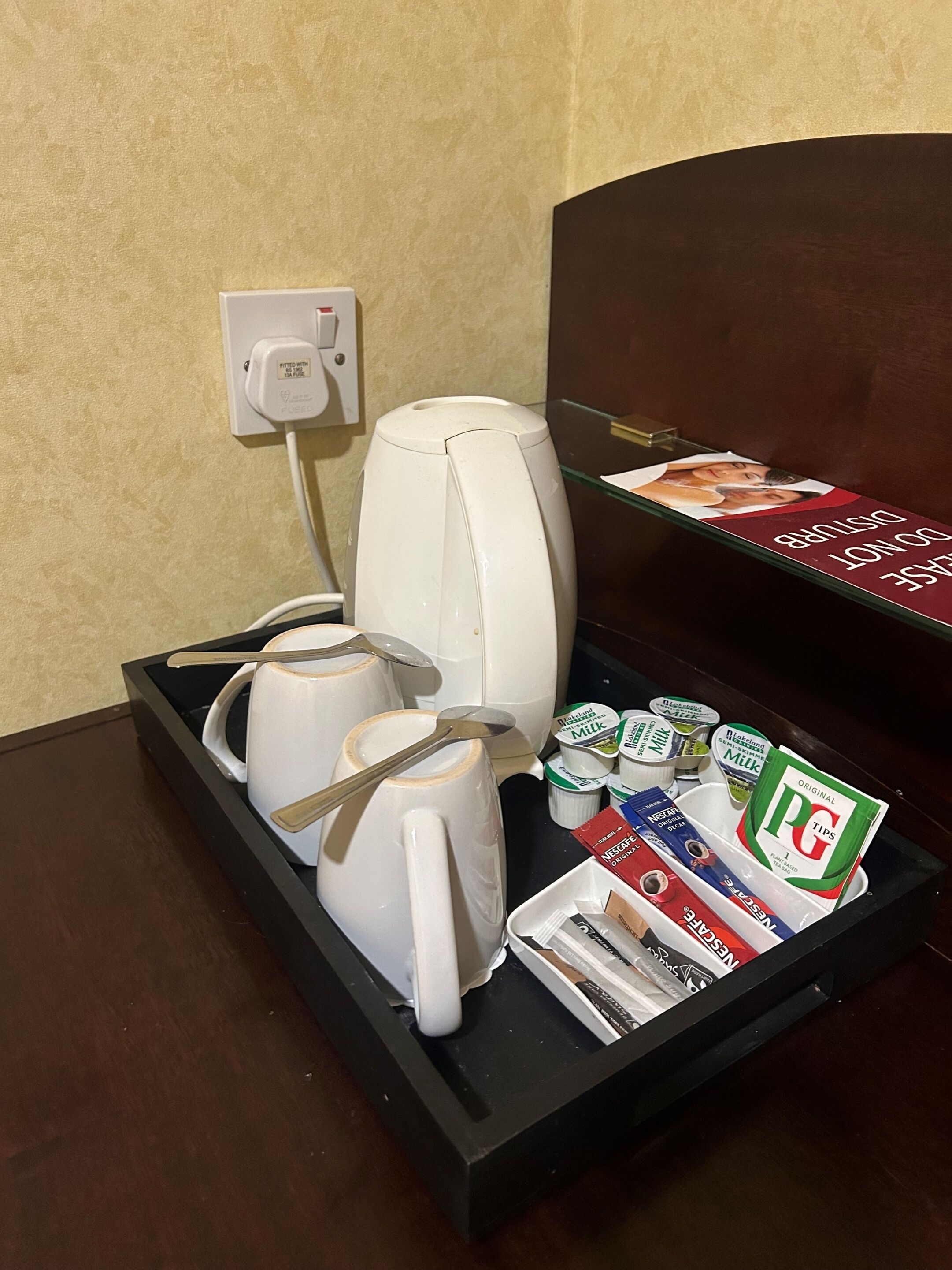 A hotel room's breakfast tray with coffee makers, mugs, and a selection of breakfast items including yogurt and cereal.