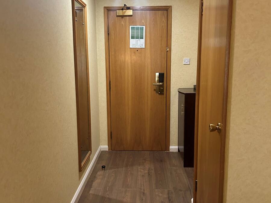 A hallway with wooden doors, a light fixture, and a small sign on the door.