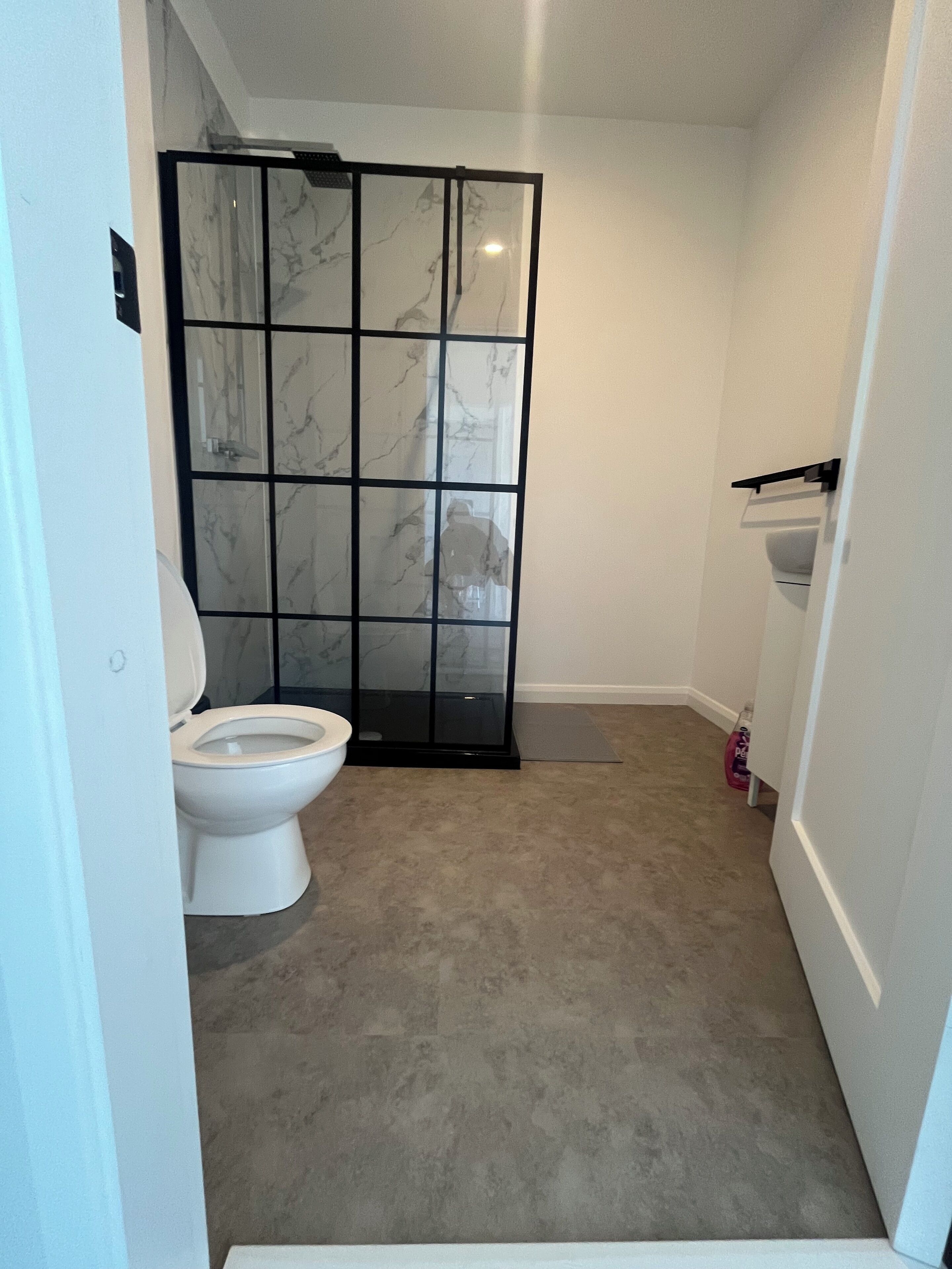 Une salle de bain comprenant des toilettes, un espace douche et un lavabo.