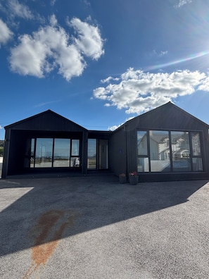 A modern building with a large glass facade, a covered entrance, and a gravel driveway. - Deerpark Villa Six Bed Four Bathrooms Sleeps Sixteen (Cashel)