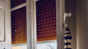 A room with a large window, wooden blinds, and a hanging wind chime. - La Piattaforma, your home with a private sea view (Santa Cesarea Terme)