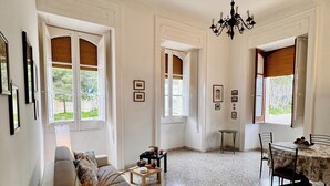 A spacious living area with a sofa, a dining table with chairs, and a chandelier. - La Piattaforma, your home with a private sea view (Santa Cesarea Terme)