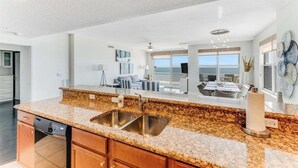 A modern kitchen with granite countertops, stainless steel sink, and wooden cabinets.