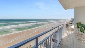 A balcony with a view of the beach and ocean.