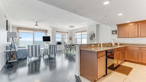 A spacious living area with a kitchen, large windows, and a balcony.