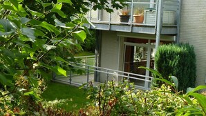 A residential building with a balcony, a small garden, and a hedge. - Stylish Ground-floor Stay (Timmendorfer Strand)