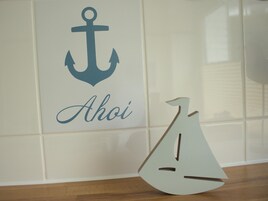 Una pared decorada con motivos náuticos que incluye un ancla y el nombre 'Ahoi'.
