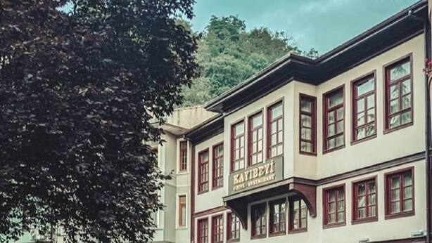 Un bâtiment traditionnel sur lequel on peut lire l’inscription suivante : « HÔTEL-RESTAURANT KAYIBEYI ».