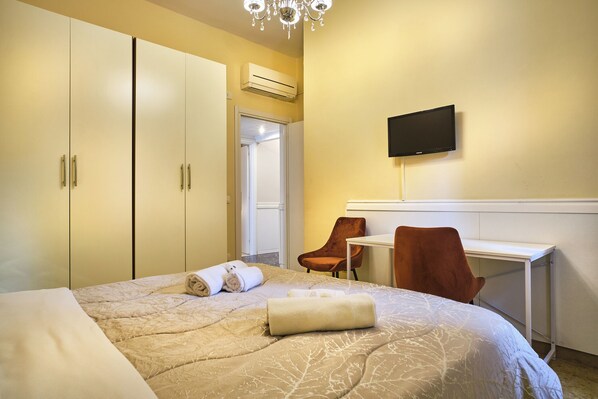 A hotel room with a bed, a desk, a chair, a TV, and a wardrobe. - Via Corfu 8 (Verona)