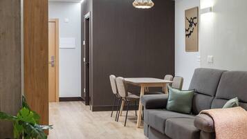 A modern living room with a sofa, a dining table with chairs, and a wooden door.
