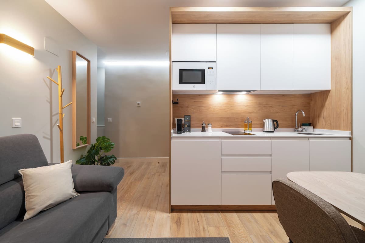 Una cocina compacta con gabinetes blancos, microondas y cafetera.