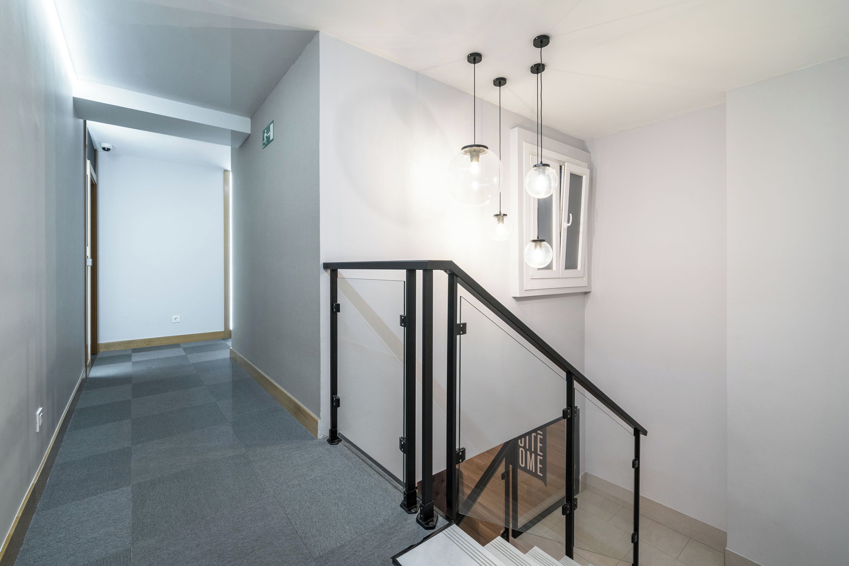 Un interior modern amb una escala, un passadís i una finestra amb vistes.
