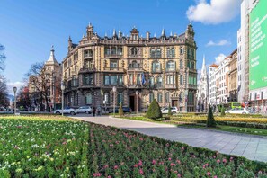 A historic building with ornate architecture, a paved walkway, and a flower garden. - Limehome Bilbao Tristan de Leguizamon (Bilbao)