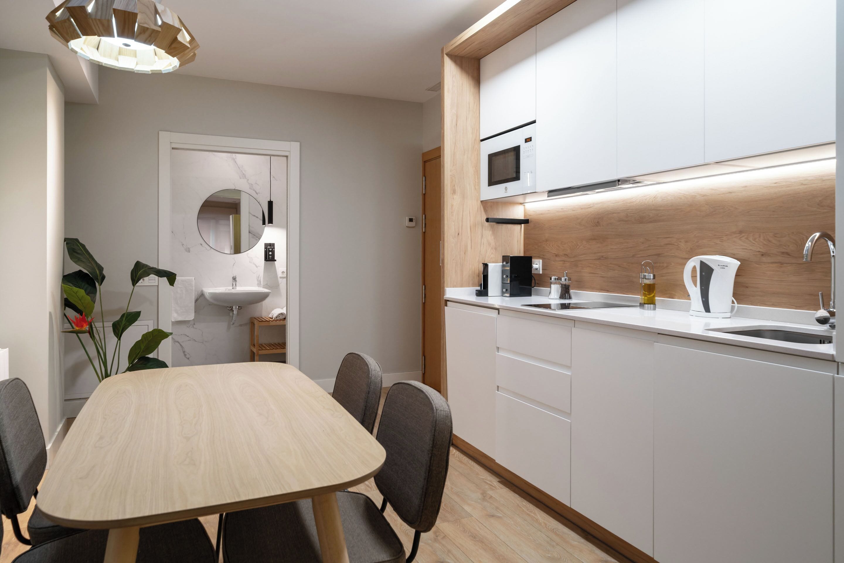 A modern kitchen with white cabinets, a wooden countertop, a microwave, a coffee maker, and a sink.