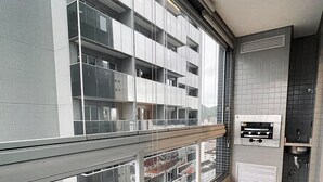 A modern apartment with a balcony, a built-in oven, and a view of the cityscape. - UNITA 157 (Praia Grande)
