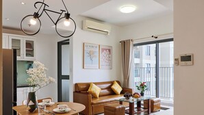 A modern living room with a dining area, wooden flooring, a sofa, a coffee table, and a hanging light fixture. - Masteri view Landmark 81, downtown city 5mins-metro (Hồ Chí Minh)