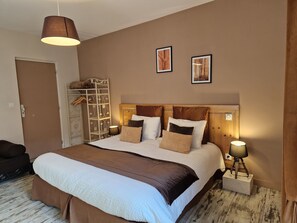 A neatly arranged bedroom with a large bed, bedside lamps, and two framed pictures on the wall. - Une autre maison (Pupillin)