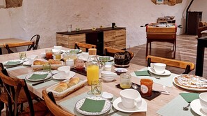 A breakfast setting with a wooden table, chairs, and various breakfast items. - Une autre maison (Pupillin)