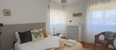 Un dormitorio con una cama, un aparador, una silla y una mesita de noche.