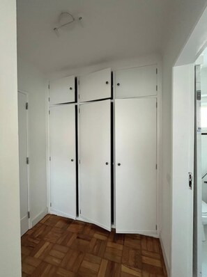 Une pièce dotée d’un parquet en bois, de murs blancs et d’une armoire blanche aux poignées noires.