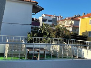 A residential area with a white building, a yellow building, and a tree in the background.