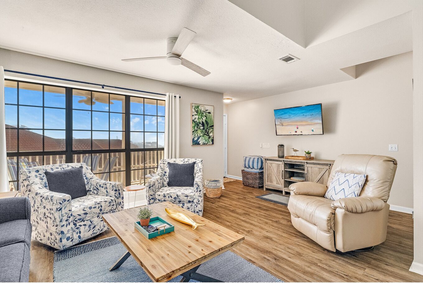 A spacious living room with a large window, a ceiling fan, and a view of the outdoors.