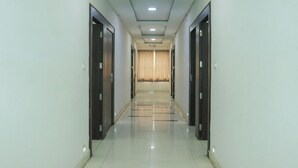 A long, narrow hallway with a tiled floor and a ceiling with recessed lighting. - Hotel River View (Khagaria)