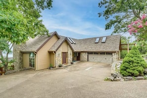 Une maison à deux étages avec une façade en pierre, un garage et une allée couverte.