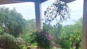 Un espace extérieur abrité, doté d’une structure en pierre, entouré de verdure et de gros rochers.