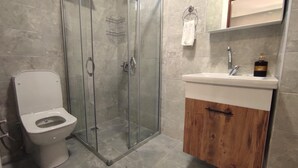 Une salle de bain avec une douche à parois de verre, des toilettes et un lavabo avec un meuble en bois.