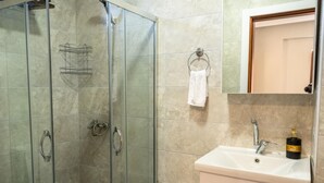 Une salle de bain avec une douche à parois de verre, un lavabo blanc et un miroir au-dessus.