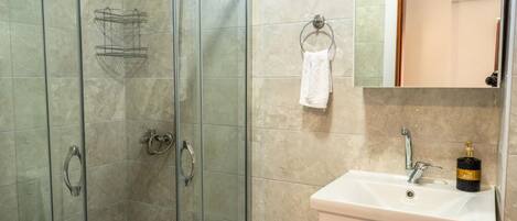 A bathroom with a glass-enclosed shower, a white sink, and a mirror above it.