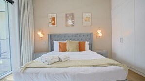 Ein modernes Schlafzimmer mit einem großen Bett, einem grauen Stoffkopfteil und zwei Wandleuchten.